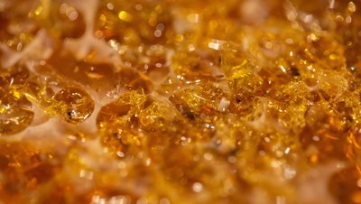 Close-up macro shot of golden amber-colored epoxy resin crystals with a translucent, glittering texture.