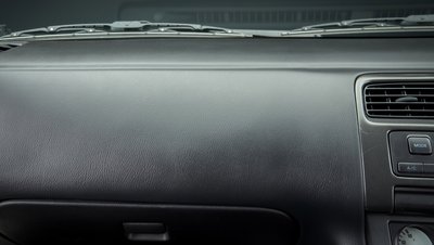Dark grey car dashboard interior showing air vents, MODE and A/C control buttons, and textured plastic surface.