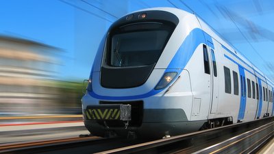Modern white and blue high-speed passenger train traveling at speed on railway tracks under clear blue sky.